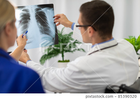 A doctor and nurse look at a photograph of a patient's lungs. A doctor and nurse look at a photograph of a patient's lungs. 85390320