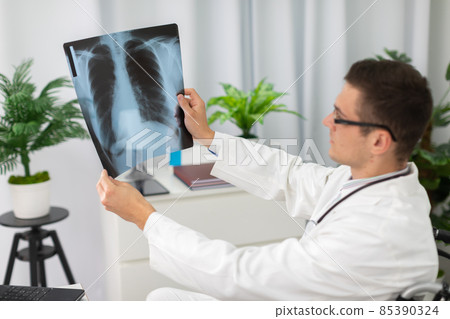 In a hospital office, a pulmonology physician checks a patient's lung x-ray. In a hospital office, a pulmonology physician checks a patient's lung x-ray. 85390324