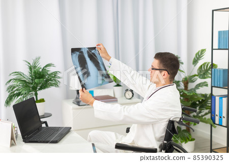 In a hospital office, a pulmonology physician checks a patient's lung x-ray. In a hospital office, a pulmonology physician checks a patient's lung x-ray. 85390325