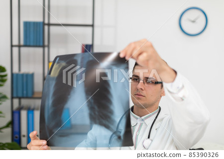 In a hospital office, a pulmonology physician checks a patient's lung x-ray. In a hospital office, a pulmonology physician checks a patient's lung x-ray. 85390326