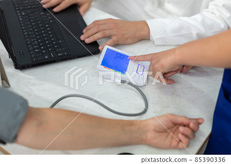The nurse indicates the result of the lower blood pressure test. 85390336