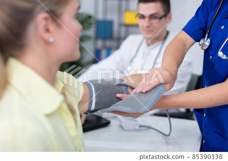 A nurse prepares a patient for a blood pressure test. 85390338