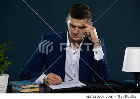 A young businessman analyzes the provisions of a contract he is about to sign with a large company. A young businessman analyzes the provisions of a contract he is about to sign with a large company. 85390382