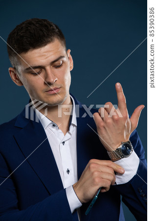 A businessman is correcting the cuff on his shirt before a meeting. A man dressed in a suit. 85390386