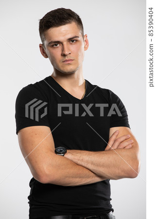 Portrait of a young handsome and serious man. A boy wearing a black t-shirt. 85390404