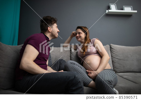 A husband moves closer to his pregnant wife and waits for a kiss. A woman in advanced pregnancy. A husband moves closer to his pregnant wife and waits for a kiss. A woman in advanced pregnancy. 85390571
