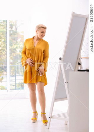 Beautiful mature woman looking at herself in large mirror indoors 85390694