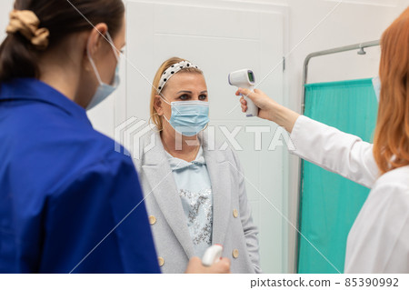 At the entrance to the clinic, the medical staff takes the temperature and disinfects the hands of all entering patients At the entrance to the clinic, the medical staff takes the temperature and disinfects the hands of all entering patients 85390992