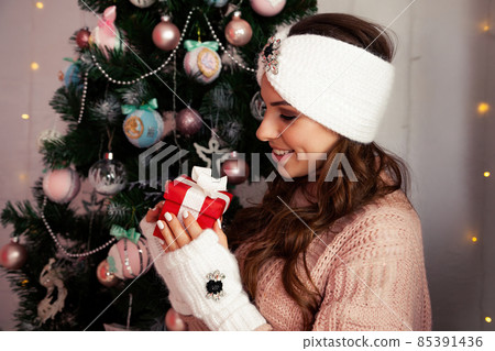Happy woman holding a gift box on the background of a Christmas tree. Portrait of a happy smiling 85391436