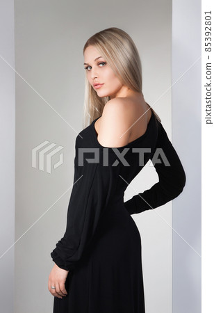young beautiful brunette in black dress on white 85392801