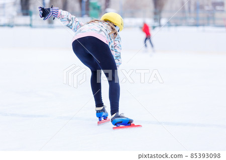Slim teenage girl skating on the ice track on short treck training 85393098