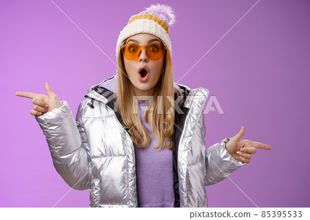 Impressed blond girl gasping widen eyes surprised folding lips wow sound check out incredible discounts winter equipment pointing left right cannot choose standing astonished purple background 85395533