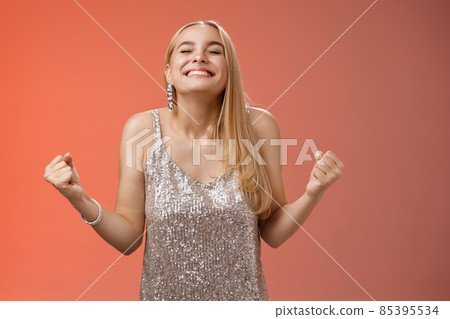 Sweet taste win. Charming happy blond girl rejoicing triumphing raise head up close eyes smiling broadly clench fists victory celebration gesture achieve dream come true, standing red background Sweet taste win. Charming happy blond girl rejoicing triumphing raise head up close eyes smiling broadly clench fists victory celebration gesture achieve dream come true, standing red background 85395534