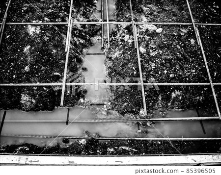 Construction site rebar suspended over a footing trench filled with rain water.  85396505