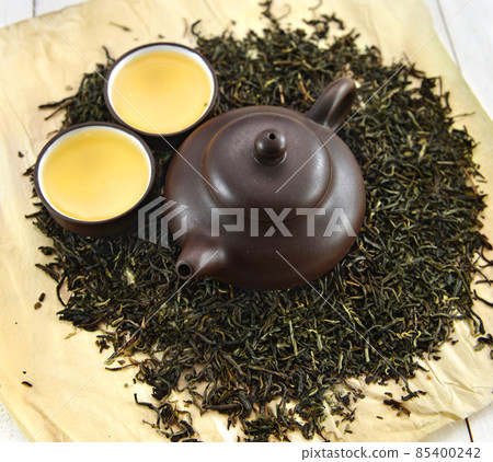 Tea cups with kettle on raw green leaves. 85400242