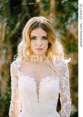 Bride in a white dress among greenery. Portrait 85400730
