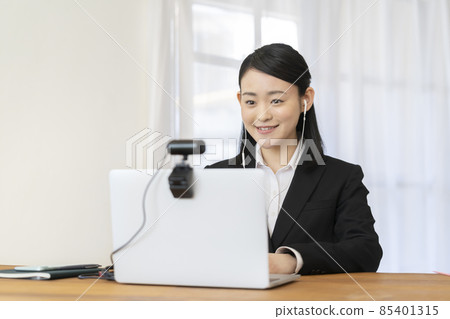 Young woman who wears earphones and talks to the webcam Job hunting online interview image 85401315