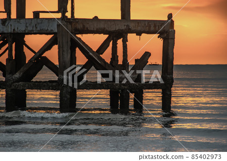 Looking out at Broken old structure remains of pier in the during beautiful twilight in the sea. Looking out at Broken old structure remains of pier in the during beautiful twilight in the sea. 85402973