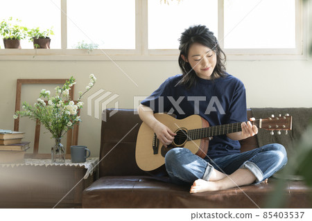A young lady playing the guitar A young lady playing the guitar 85403537