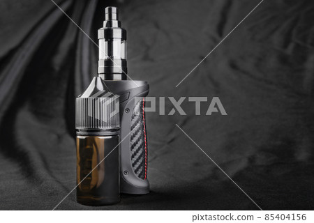Black vape with oil on a black background close-up. Black vape with oil on a black background close-up. 85404156