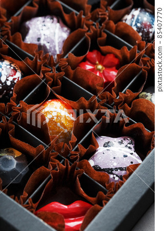 Colorful handmade chocolates in a box on a dark background Colorful handmade chocolates in a box on a dark background 85407770
