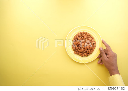 top view of almond on a plate on yellow background top view of almond on a plate on yellow background 85408462