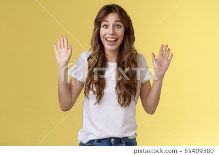 Cheerful glad outgoing cute positive young girl smiling broadly raise both palms waving hands hello greeting gesture welcome friend guest smiling hi gladly invite come inside yellow background Cheerful glad outgoing cute positive young girl smiling broadly raise both palms waving hands hello greeting gesture welcome friend guest smiling hi gladly invite come inside yellow background 85409380