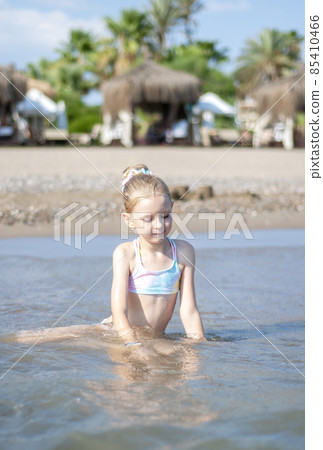 Little girl playing on the beach by the sea Little girl playing on the beach by the sea 85410466