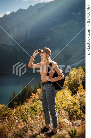Wanderlust and travel concept. Stylish traveler girl in cap looking in front of mountain Wanderlust and travel concept. Stylish traveler girl in cap looking in front of mountain 85410467