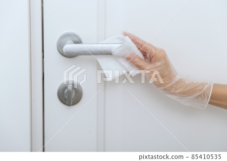 Cleaning door handles with wet wipe and white gloves. Woman hand using towel for cleaning home room door link. Sanitize surfaces prevention in hospital and public spaces against corona virus. Cleaning door handles with wet wipe and white gloves. Woman hand using towel for cleaning home room door link. Sanitize surfaces prevention in hospital and public spaces against corona virus. 85410535