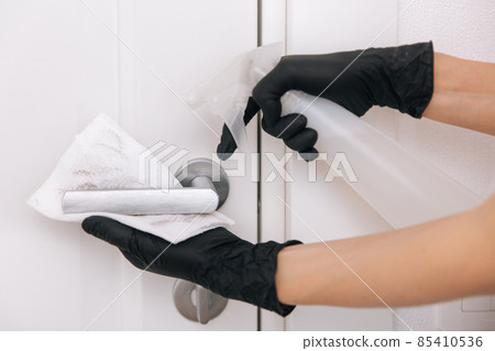 Cleaning door handle with dirty wipe in black gloves and sanitizer spray. Disinfection in hospital and public spaces against corona virus. Woman hand using towel for cleaning. Cleaning door handle with dirty wipe in black gloves and sanitizer spray. Disinfection in hospital and public spaces against corona virus. Woman hand using towel for cleaning. 85410536