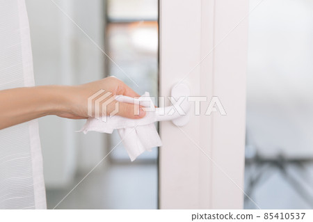 Cleaning door handles with an antiseptic wet wipe and gloves. Woman hand using towel for cleaning home room door link. Sanitize surfaces prevention in hospital and public spaces against corona virus. Cleaning door handles with an antiseptic wet wipe and gloves. Woman hand using towel for cleaning home room door link. Sanitize surfaces prevention in hospital and public spaces against corona virus. 85410537