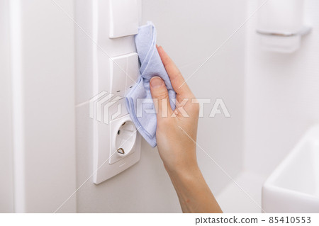 Cleaning switches and sockets with a microfiber cloth. Woman hand using wet wipe for cleaning home room door link. Sanitize surfaces prevention in hospital and public spaces against corona virus. Cleaning switches and sockets with a microfiber cloth. Woman hand using wet wipe for cleaning home room door link. Sanitize surfaces prevention in hospital and public spaces against corona virus. 85410553