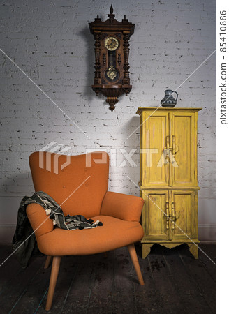 Vintage orange armchair, yellow cupboard, pendulum clock and black scarf 85410886