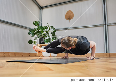 Athletic woman doing the advanced yoga posture Crow pose, kakasana. Athletic woman doing the advanced yoga posture Crow pose, kakasana. 85412017