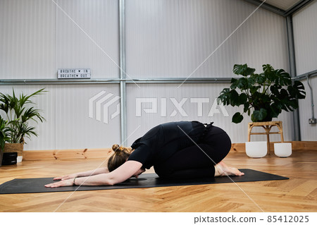 yoga trainer stretching on mat in interior studio yoga trainer stretching on mat in interior studio 85412025