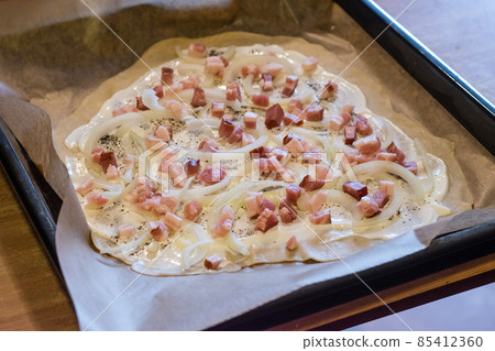Raw flammkuchen with onion and bacon on the top. 85412360