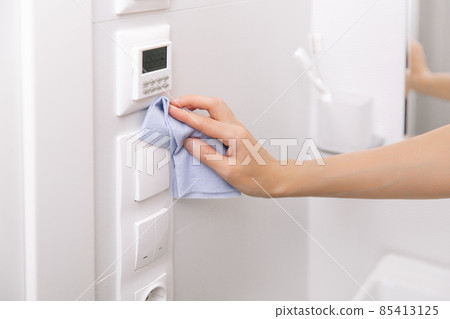 Cleaning switches and sockets with a microfiber cloth. Sanitize surfaces prevention in hospital and public spaces against corona virus. Woman hand using wet wipe for cleaning home room door link. 85413125