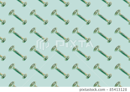 Pattern made with jade gua sha facial roller on pastel green background. Facial massage kit for lifting massage therapy made from natural stones, personal skin care anti-aging tools. 85413128
