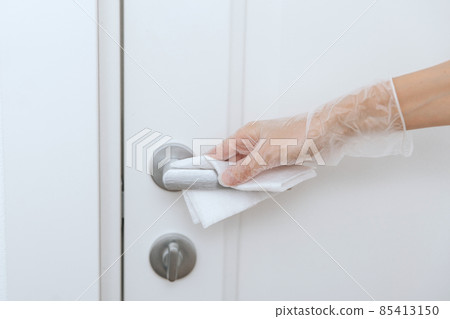 Cleaning door handles with wet wipe and white gloves. Sanitize surfaces prevention in hospital and public spaces against corona virus. Woman hand using towel for cleaning home room door link. Cleaning door handles with wet wipe and white gloves. Sanitize surfaces prevention in hospital and public spaces against corona virus. Woman hand using towel for cleaning home room door link. 85413150
