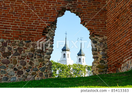 ancient stone and red brick castle ruins with church towers in the background ancient stone and red brick castle ruins with church towers in the background 85413383