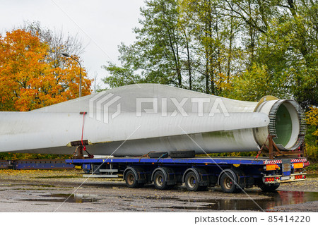 A view of a truck, a low-loader semi-trailer with oversized wind generator parts in the parking lot 85414220