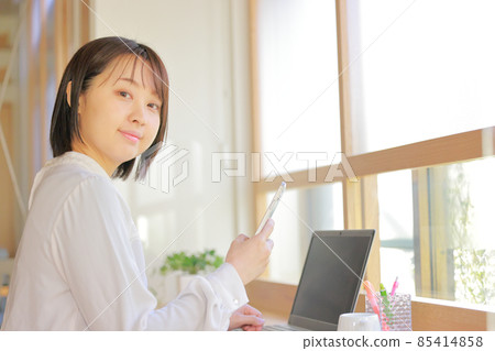 Office window seat_Woman who raised her face from her smartphone 1 Office window seat_Woman who raised her face from her smartphone 1 85414858