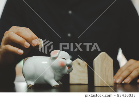 male hand holding a coin in a white pig piggy bank. Business concepts, finance, savings, taxes and retirement investments 85416035