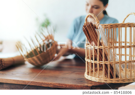 Woman weaves basket of paper tubes on wooden table Woman weaves basket of paper tubes on wooden table 85418806