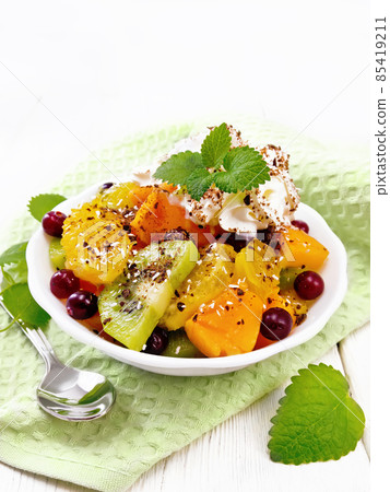 Salad fruit with cranberries in bowl on wooden board 85419211