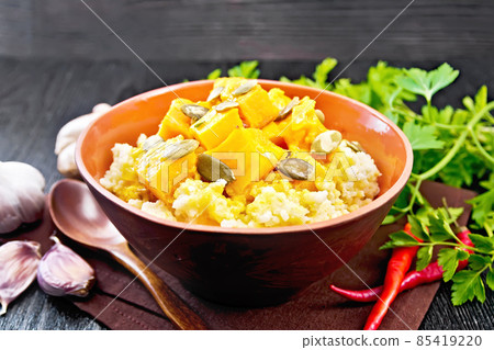 Porridge millet with spicy pumpkin in clay bowl on black board Porridge millet with spicy pumpkin in clay bowl on black board 85419220