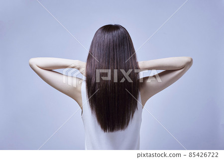 A woman's back as she pushes her long hair back. A woman's back as she pushes her long hair back. 85426722