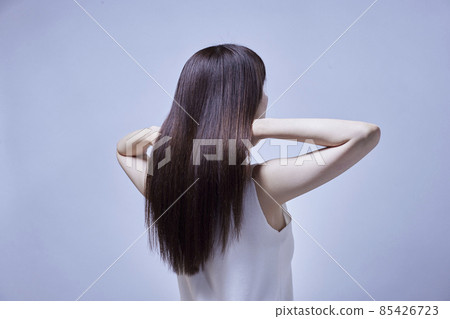 A woman's back as she touches her long hair. A woman's back as she touches her long hair. 85426723