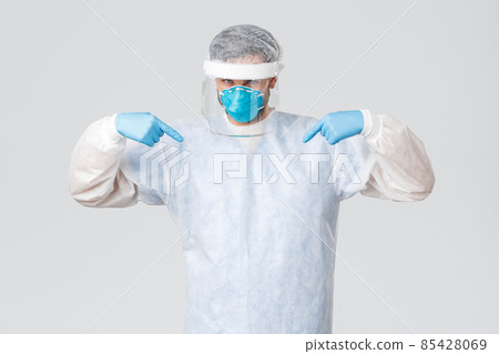 Covid-19, pandemic, healthcare workers fighting virus outbreak. Confident young doctor in medical mask, rubber gloves and personal protective equipment pointing at himself, saving lives of patients Covid-19, pandemic, healthcare workers fighting virus outbreak. Confident young doctor in medical mask, rubber gloves and personal protective equipment pointing at himself, saving lives of patients 85428069
